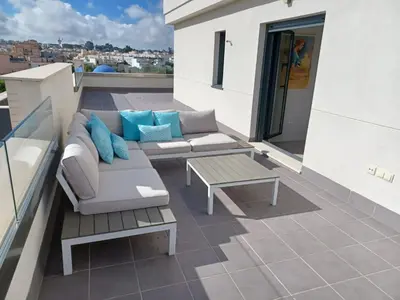 a patio with a couch and a table on a roof at Atico Costa Doñana in Sanlúcar de Barrameda
