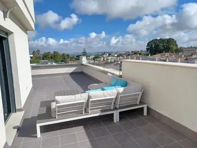 a balcony with a couch and chairs on a roof at Atico Costa Doñana in Sanlúcar de Barrameda