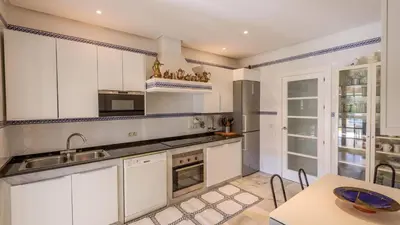 a kitchen with white cabinets and a sink and a table at Villa con Encanto Conil de la Frontera by Ruralidays in Conil de la Frontera