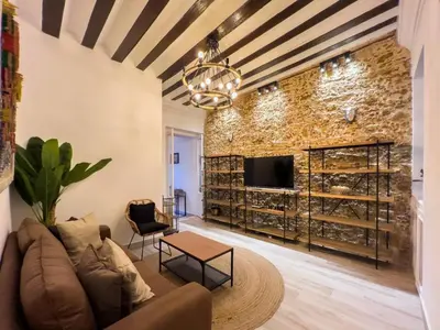 a living room with a brick wall and a couch and a table at El Destino Corazón de Cádiz Grupo AC Gestion in Cádiz