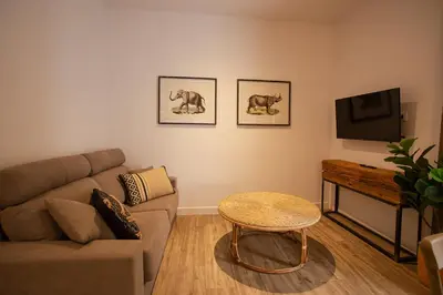 a living room with a couch and a table and a tv at Loft Deluxe Herrería 6 - Vivienda Vacacional. in El Puerto de Santa María