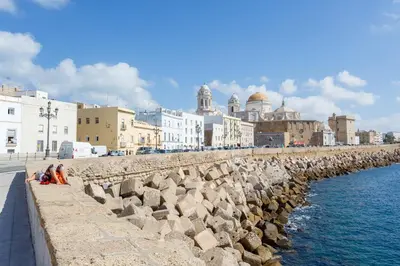 a group of people sitting on a wall next to the water at SERENISSIMA Apartment by Cadiz4Rentals in Cádiz
