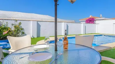 a glass table with a bottle and wine glasses on it at Villa Brenda Conil de la Frontera by Ruralidays in Conil de la Frontera