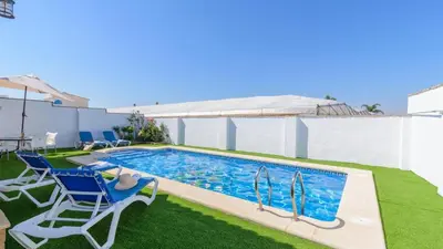 a swimming pool with two chairs and a table at Villa Brenda Conil de la Frontera by Ruralidays in Conil de la Frontera
