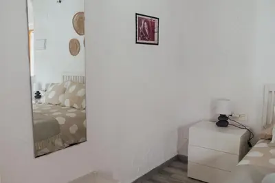 a bedroom with a mirror on a white wall at APARTAMENTO EL NANO in Jerez de la Frontera