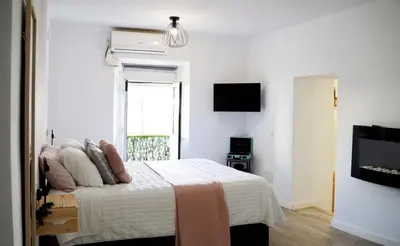 a white bedroom with a bed and a television at Amores Loft Rural in Alcalá de los Gazules