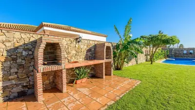 a brick oven in a yard next to a pool at Apto El Descanso I Conil de la Frontera by Ruralidays in Conil de la Frontera
