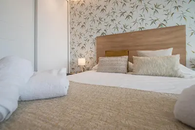 a bedroom with a large bed with white sheets and pillows at Apartamento La Atalaya de Cádiz in Cádiz