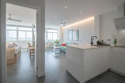 a kitchen with white cabinets and a living room at Apartamento La Atalaya de Cádiz in Cádiz