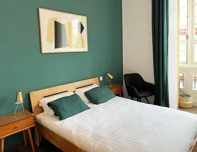 a bedroom with a bed with two green pillows at Casa Odisea Cádiz in Cádiz