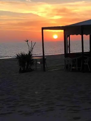 a picnic shelter on the beach with the sunset at Luz, sol y arena in Rota