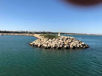 a lighthouse on a rocky island in the water at Luz, sol y arena in Rota