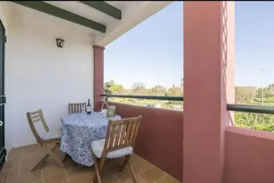 a room with a table and chairs on a balcony at apartamento playa la barrosa in Chiclana de la Frontera