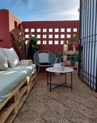 a balcony with a bed and a table on a patio at apartamento playa la barrosa in Chiclana de la Frontera