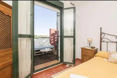 a bedroom with a bed and a large glass window at apartamento playa la barrosa in Chiclana de la Frontera