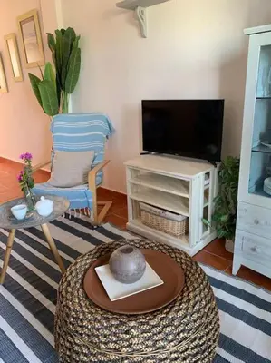 a living room with a tv and a table and a chair at apartamento playa la barrosa in Chiclana de la Frontera