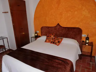 a bedroom with a large white bed with an orange headboard at Hotel La Fonda del Califa in Arcos de la Frontera