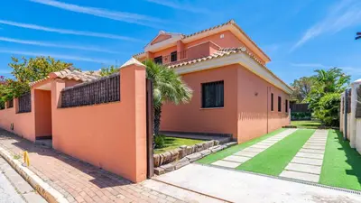 a pink house with a green lawn in front of it at Villa Italia Conil de la Frontera by Ruralidays in Conil de la Frontera