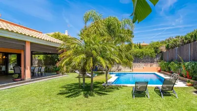 a backyard with a palm tree and a swimming pool at Villa Italia Conil de la Frontera by Ruralidays in Conil de la Frontera