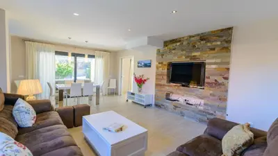 a living room with a couch and a tv on a brick wall at Villa Mónaco Conil de la Frontera by Ruralidays in Conil de la Frontera