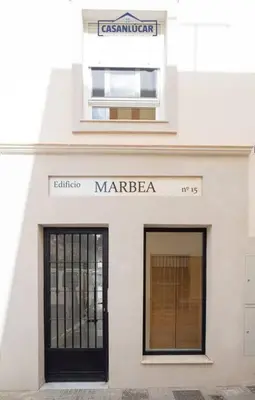 a white building with two windows and a door at Casa Alcoba de la luz in Sanlúcar de Barrameda