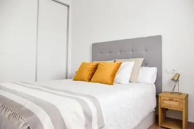 a bedroom with a large white bed with orange pillows at Apartamento Residencial Punta Candor in Rota