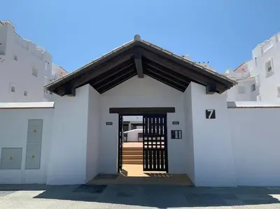 a white building with a gate in the middle at Apartamento Residencial Punta Candor in Rota