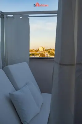 a bed and a window with a view of a city at El Anfitrión - Barra del río in Sanlúcar de Barrameda