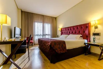 a hotel room with a large bed and a desk at Exe Guadalete in Jerez de la Frontera