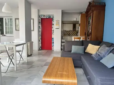 a living room with a couch and a table and a red door at PENTHOUSE WITH LARGE TERRACE IN CENTER OF CÁDIZ in Cádiz
