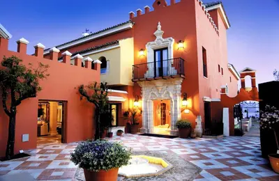a large orange building with a courtyard with potted plants at Soho Boutique Vistahermosa in El Puerto de Santa María