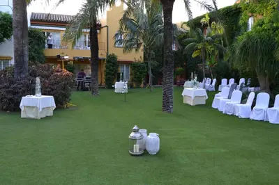 a courtyard with white tables and chairs and palm trees at Soho Boutique Vistahermosa in El Puerto de Santa María