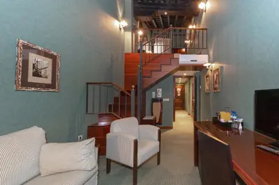 a living room with a staircase and white chairs at Soho Boutique Jerez in Jerez de la Frontera