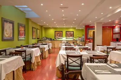 a restaurant with white tables and chairs and green walls at Soho Boutique Jerez in Jerez de la Frontera