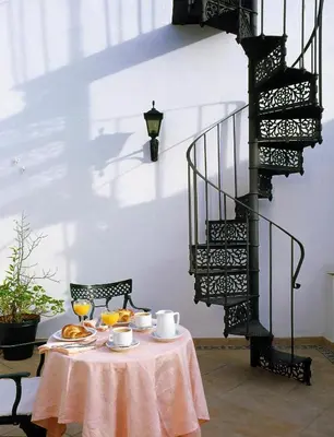 a table with a pink table cloth and a staircase at Hotel Los Olivos in Arcos de la Frontera