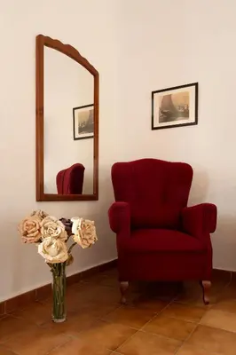 a living room with a red chair and a mirror at Hotel Los Olivos in Arcos de la Frontera