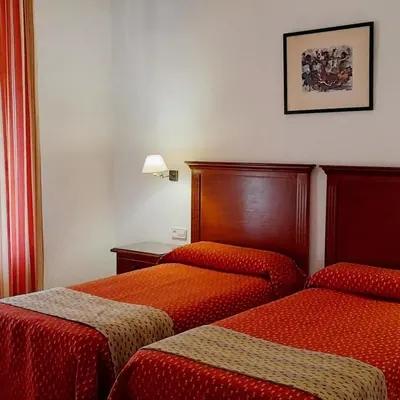 a hotel room with two beds with red sheets at Hotel Los Olivos in Arcos de la Frontera