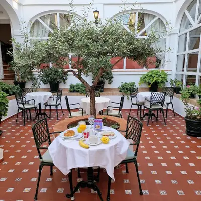 a patio with tables and chairs and a tree at Hotel Los Olivos in Arcos de la Frontera