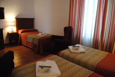 a hotel room with two beds and a window at Hotel Los Olivos in Arcos de la Frontera