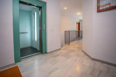 an empty hallway with a green door and wooden floors at Wehost-costaluz Apartamento Sanlúcar con parking in Sanlúcar de Barrameda