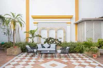 a patio with chairs and a couch and palm trees at Soho Boutique Puerto in El Puerto de Santa María