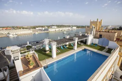 a large swimming pool on top of a building next to the water at Soho Boutique Puerto in El Puerto de Santa María