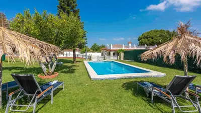 a yard with a swimming pool with chairs and umbrellas at Los Arcángeles Chiclana de la Frontera by Ruralidays in Chiclana de la Frontera