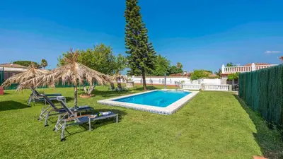 a backyard with a swimming pool with chairs and a umbrella at Los Arcángeles Chiclana de la Frontera by Ruralidays in Chiclana de la Frontera
