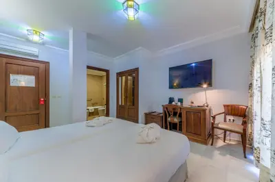 a bedroom with a bed and a desk and a chair at Hotel Playa de Regla in Chipiona