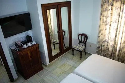 a room with a bed and a mirror and a chair at Hotel Playa de Regla in Chipiona