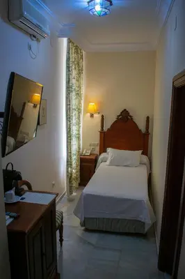 a bedroom with a bed and a television and a desk at Hotel Playa de Regla in Chipiona