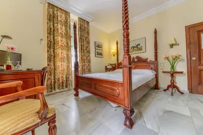 a bedroom with a four poster bed and a chair at Hotel Playa de Regla in Chipiona