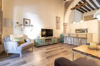 a living room with a couch a table and a kitchen at Loft Bodega San Blas con porche y parking in Jerez de la Frontera