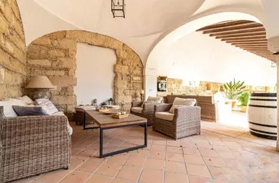 a living room with wicker furniture and a stone wall at Loft Bodega San Blas con porche y parking in Jerez de la Frontera